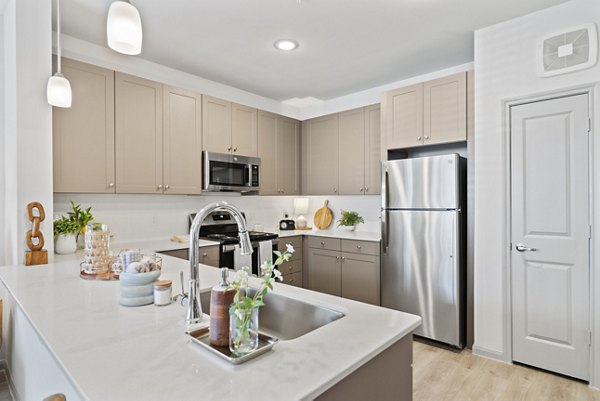 Modern kitchen with stainless steel appliances and granite countertops in Emerson at Trace Apartments