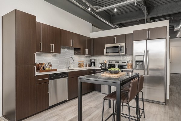 Modern kitchen with stainless steel appliances and breakfast bar at The Lofts at Westgate Apartments