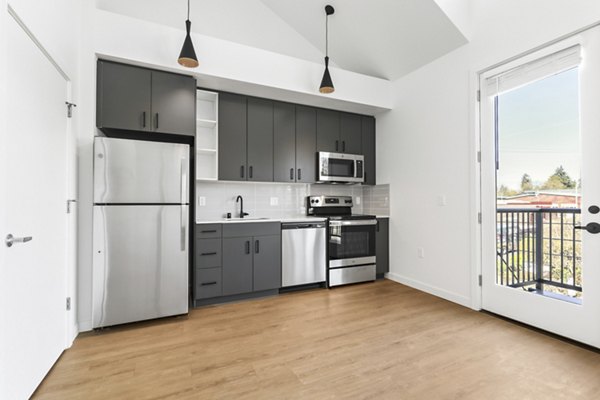 Modern kitchen with stainless steel appliances and marble countertops at Hudson West Apartments