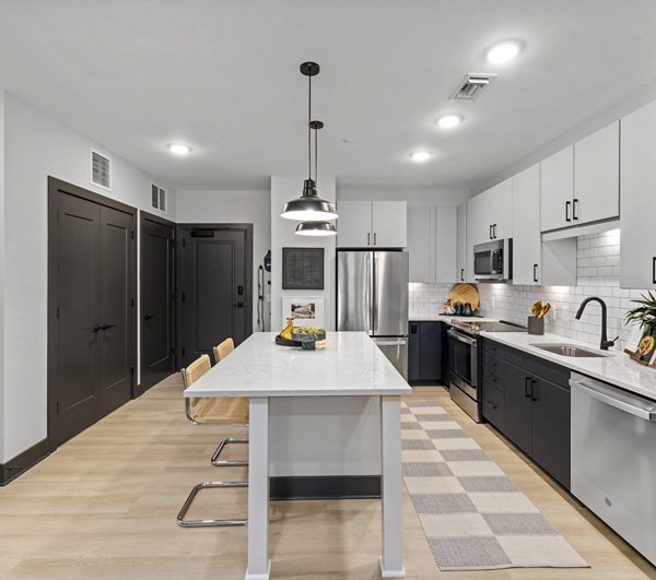 Modern kitchen with stainless steel appliances and granite countertops in The Miles Apartments