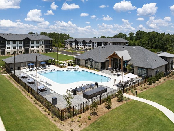 Relaxing poolside area at Arcadia at Symphony Park Apartments with lounge chairs and surrounding greenery