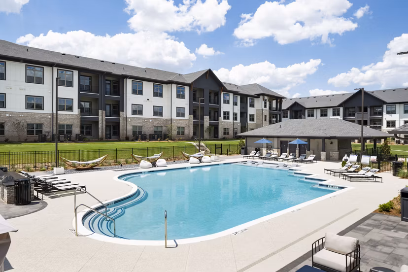 Relaxing pool area at Arcadia at Symphony Park Apartments with sun loungers and lush landscaping, offering a luxury retreat for residents