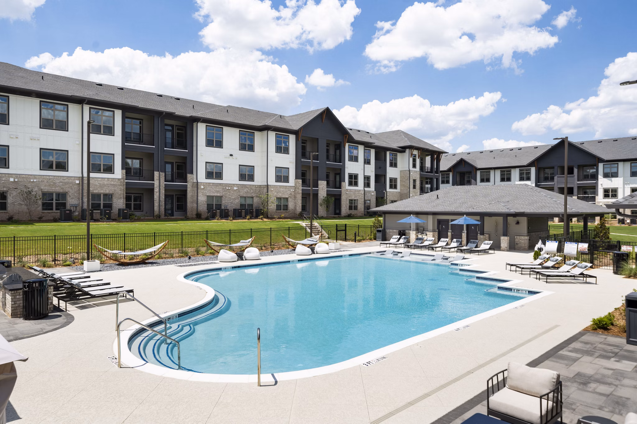 Relaxing pool area at Arcadia at Symphony Park Apartments with sun loungers and lush landscaping, offering a luxury retreat for residents