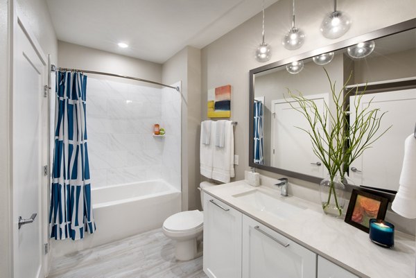 Bathroom with sleek modern fixtures at SUR Lake Buena Vista Apartments, featuring a large mirror and elegant lighting