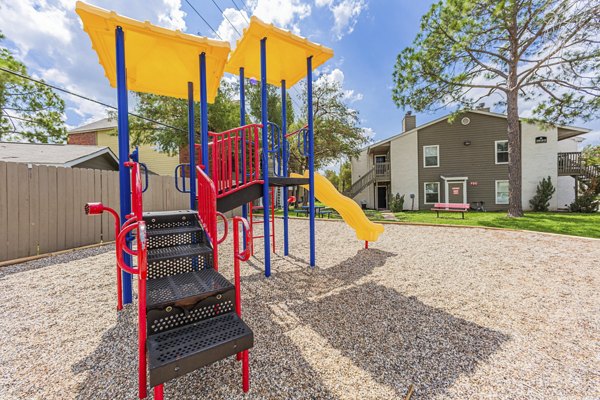 Playground designed for family fun at Circle at Point Park Apartments, featuring swings and slides in a kid-friendly outdoor setting