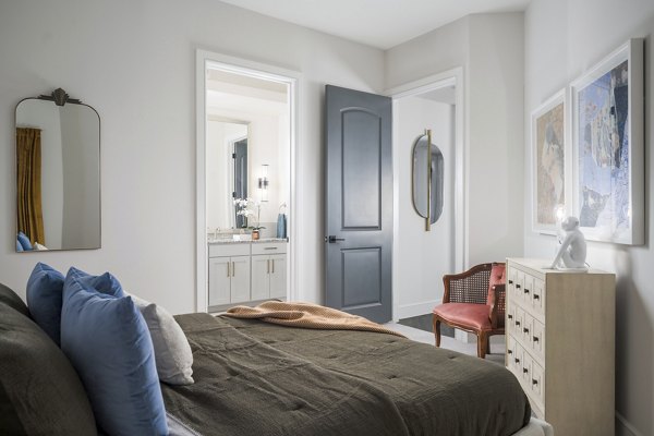 Spacious bedroom with modern decor at The Margo Apartments, featuring a plush bed and large windows providing natural light Luxury living at its finest