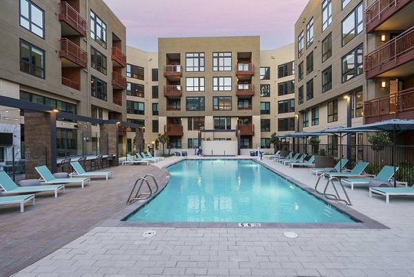 Relaxing pool area with lounge chairs at Rowe at Pear Village Apartments, offering a serene outdoor space for leisure and enjoyment