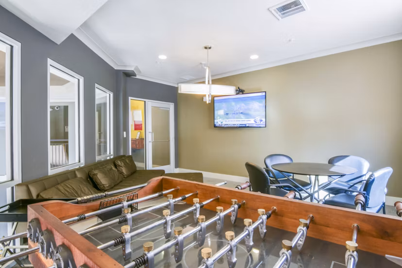 Game room featuring a foosball table, cozy couch, and wall-mounted TV in luxury apartments