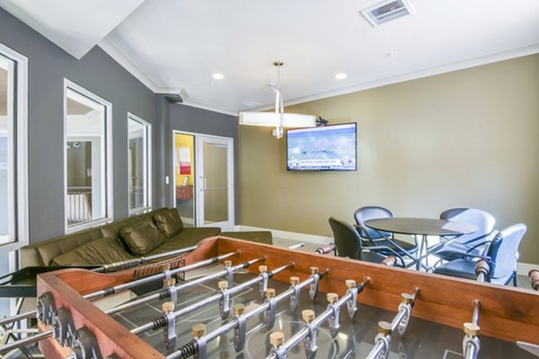 Game room featuring a foosball table, cozy couch, and wall-mounted TV in luxury apartments