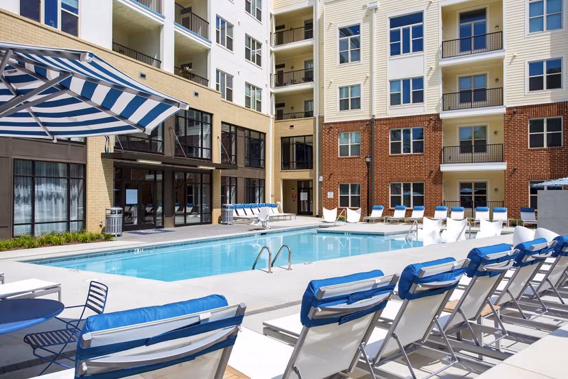 Luxury pool area at 5115 Park Place Apartments featuring lounge chairs and greenery