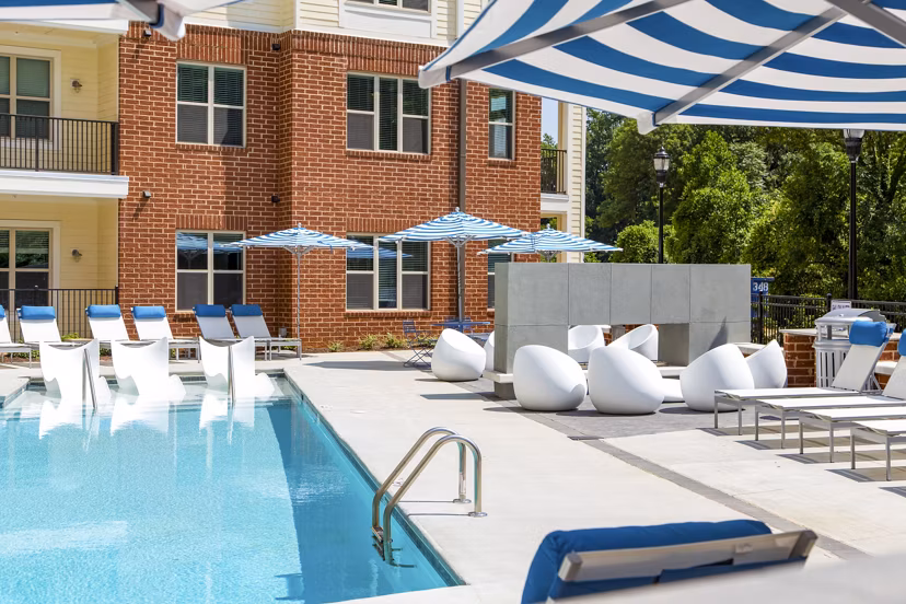 Luxurious pool area at 5115 Park Place Apartments featuring modern lounge chairs and landscaping