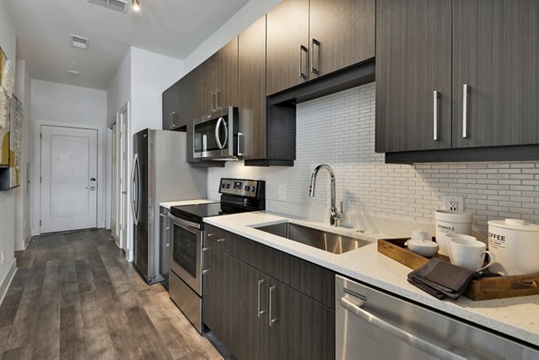 Modern kitchen with stainless steel appliances and granite countertops at 675 N Highland Apartments