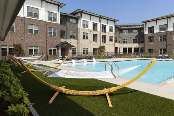 Outdoor pool surrounded by lush landscaping at Alta Ashley Park Apartments, offering a relaxing retreat for residents