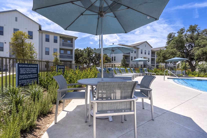 Tranquil outdoor pool area at Alta Berry Creek Apartments with lounging chairs and landscaped surroundings