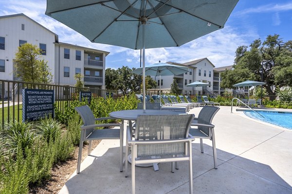 Tranquil outdoor pool area at Alta Berry Creek Apartments with lounging chairs and landscaped surroundings