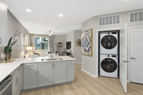 Modern kitchen and living area with stacked washer and dryer in luxury apartment