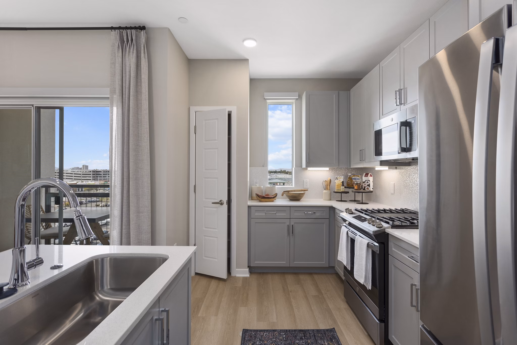Modern kitchen with stainless steel appliances and gray cabinets in luxury apartment