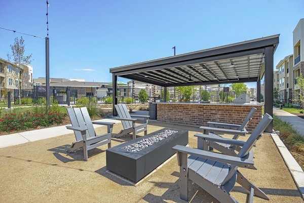 Outdoor recreation space with picnic tables and greenery at Alta Denton Station Apartments