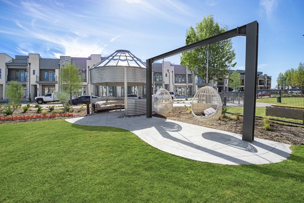 Recreation area with modern design at Alta at the Farm Apartments featuring lush greenery and seating areas
