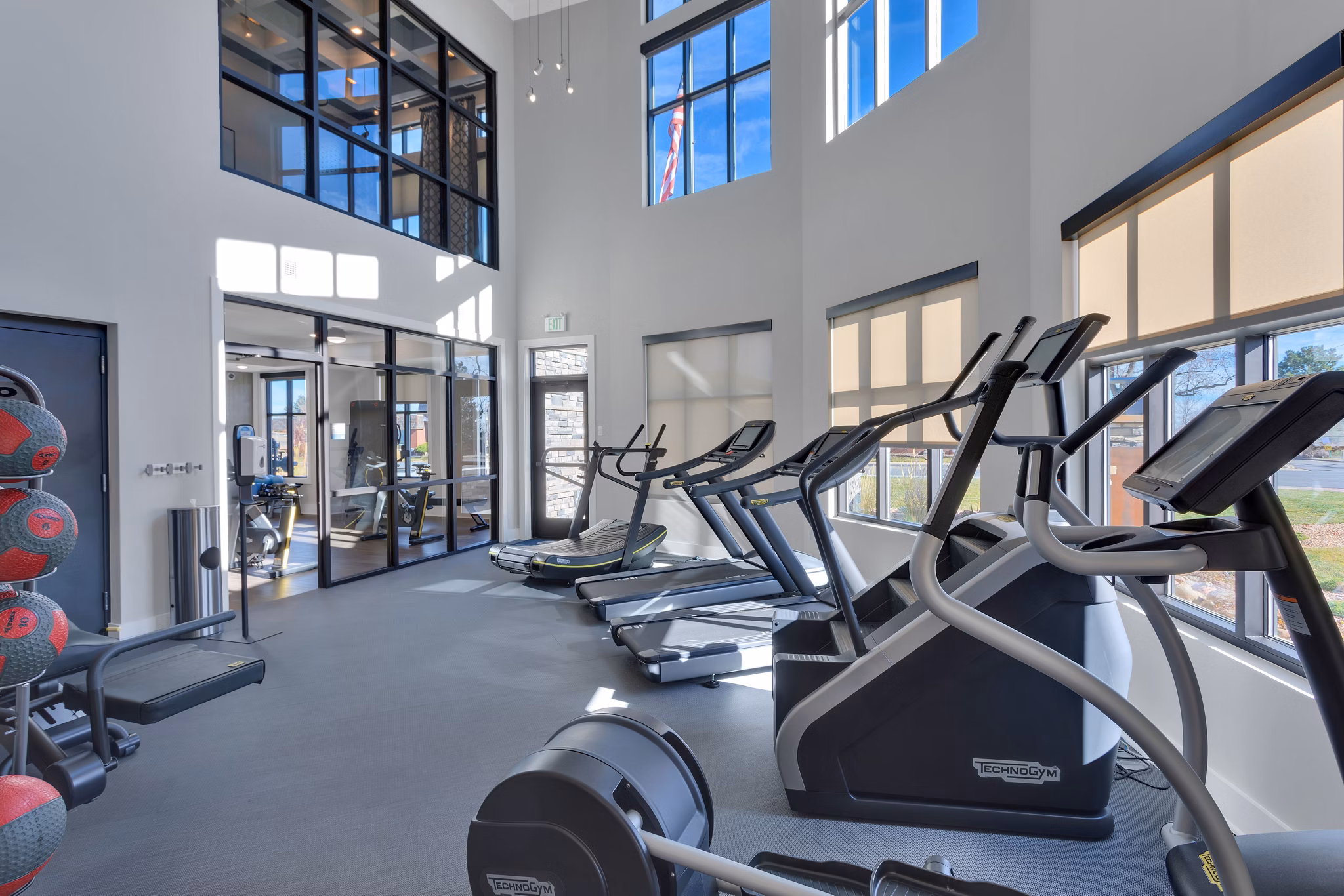 Spacious gym with exercise machines and large windows at Harbor 1500 Apartments