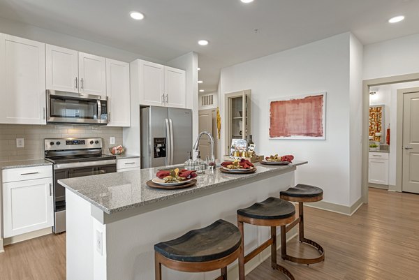 Modern kitchen with stainless steel appliances and breakfast bar in Alta Landing Apartments, luxury living space