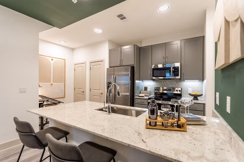 Modern kitchen with sleek countertops and stainless steel appliances at Alta Sergeant Apartments, luxury living by Greystar