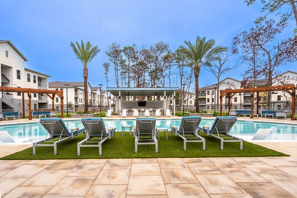 Resort-style pool surrounded by lush landscaping at Alta Sergeant Apartments, offering luxury living