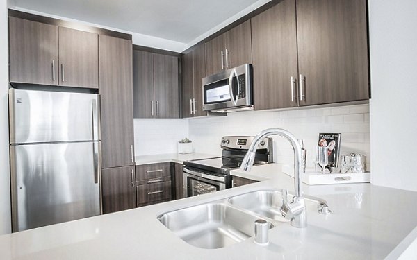 Modern kitchen featuring stainless steel appliances and granite countertops in Alta South Bay Apartments