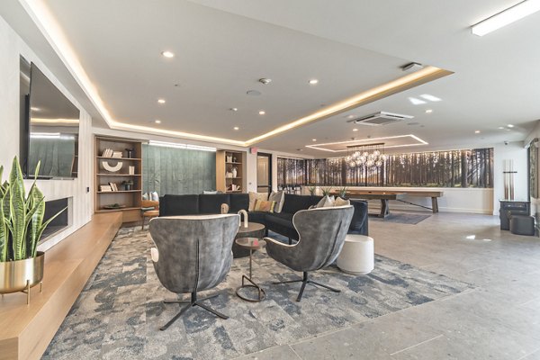 Clubroom with modern furnishings and game tables at Alta University Place Apartments, offering a social space for residents in a luxury setting