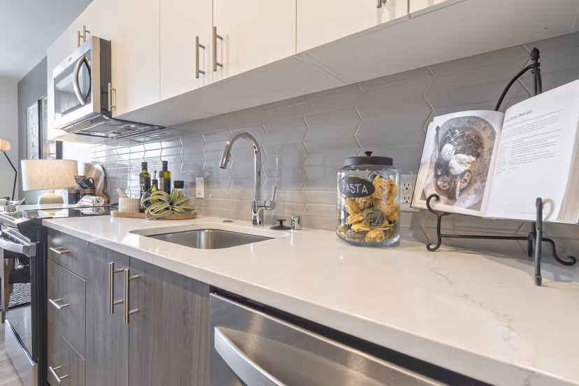 Modern kitchen featuring stainless steel appliances and quartz countertops at Alta University Place Apartments