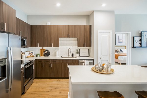 Modern kitchen with stainless steel appliances and quartz countertops at Alta Wren Apartments