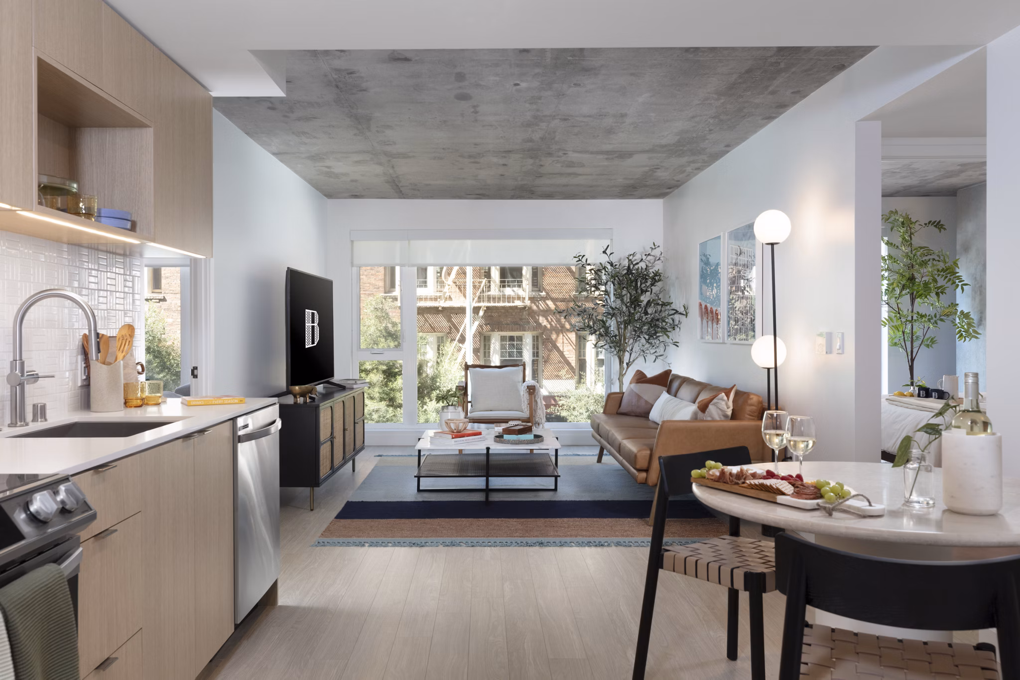 Spacious living room with modern decor, large windows, and hardwood floors at The Brady apartments