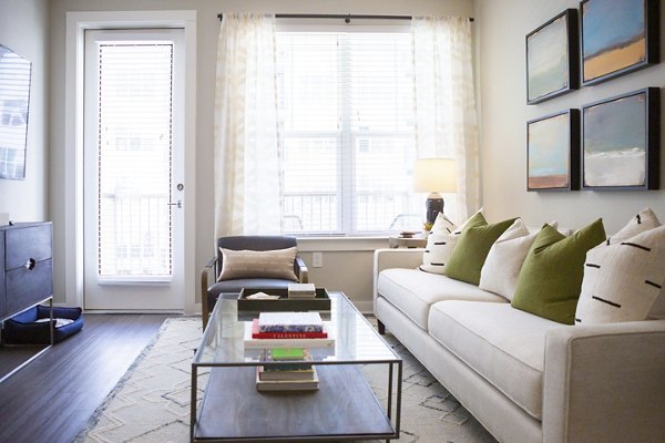 Modern living room with sleek furniture and large windows at Elden Galleria Apartments