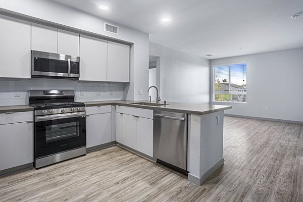 Modern kitchen with island and stainless steel appliances at Jefferson Cenza Apartments
