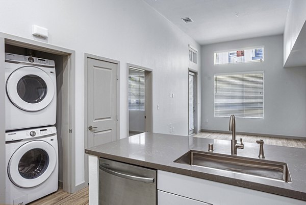 Modern kitchen with stainless steel appliances and in-unit laundry at Jefferson Cenza Apartments