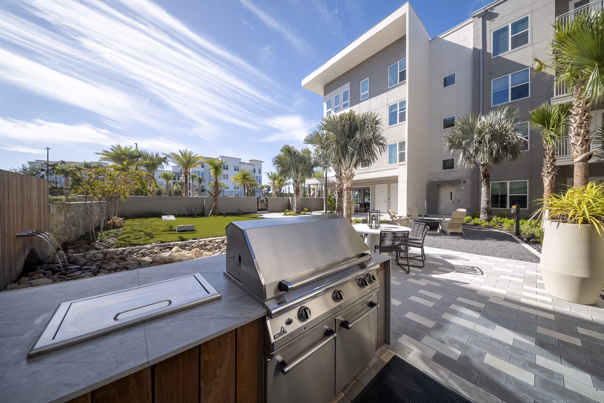 Patio with cozy seating and lush greenery at Novel Nona Apartments, offering a tranquil outdoor space for residents to relax and unwind