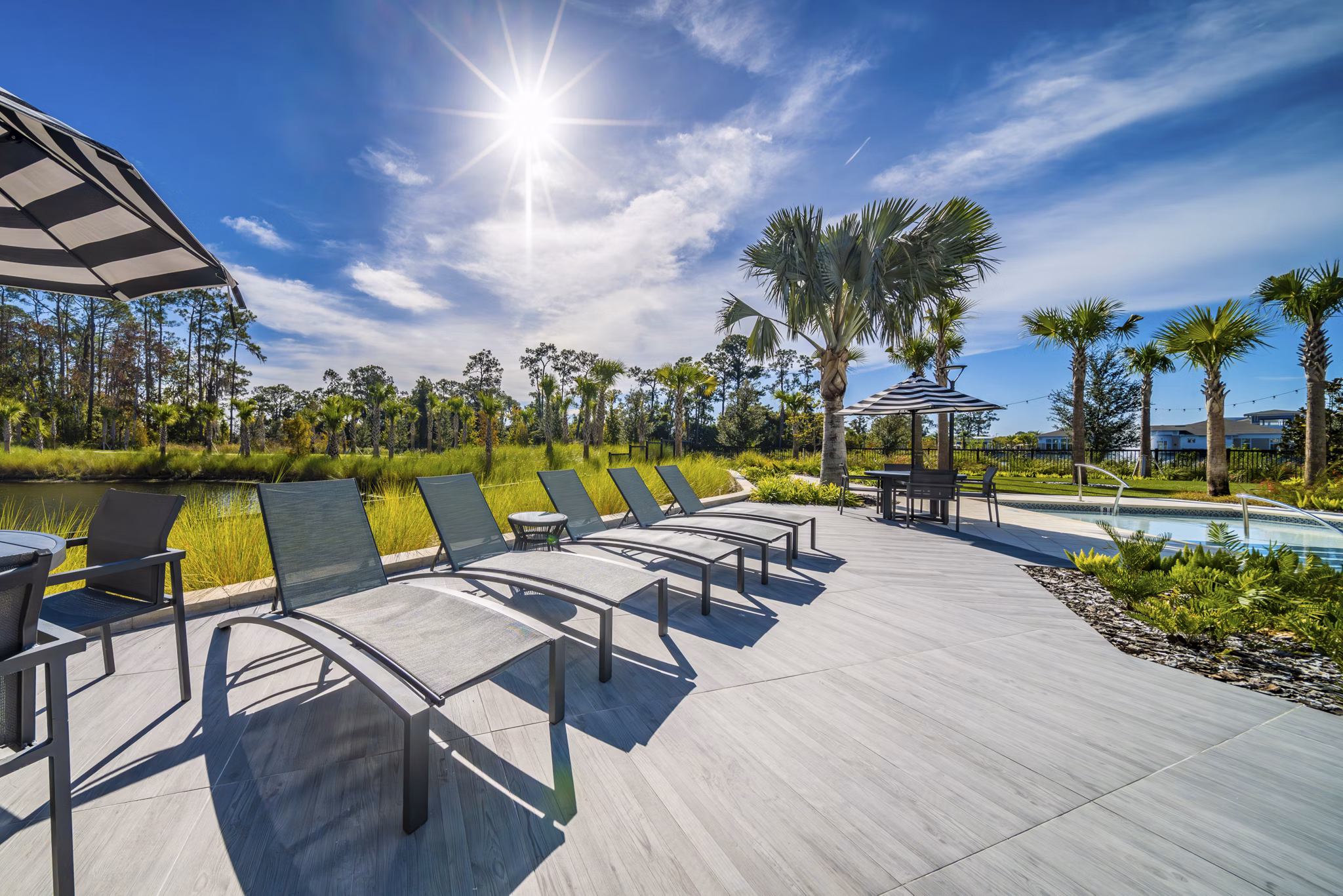 Refreshing outdoor pool at Novel Nona Apartments with lounge seating and lush greenery, perfect for relaxation and leisure activities