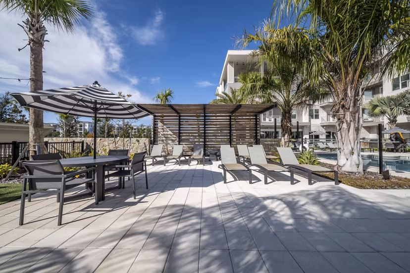Luxury resort-style pool at Novel Nona Apartments, featuring modern loungers and lush landscaping