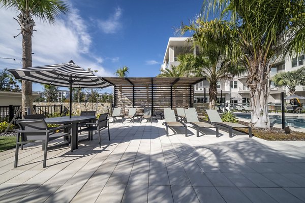 Luxury resort-style pool at Novel Nona Apartments, featuring modern loungers and lush landscaping