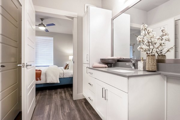 Cozy bedroom featuring stylish decor and large windows at Luxe at Mile High luxury apartments