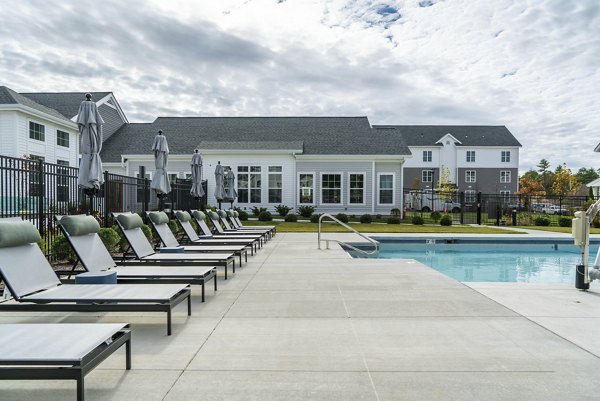 Serene outdoor pool surrounded by lush greenery at The Madison at Marshfield apartments