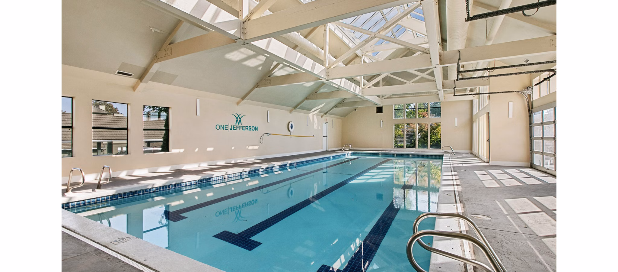 Luxurious poolside oasis at One Jefferson Apartments with sun loungers and landscaped gardens, ideal for relaxation and leisure activities