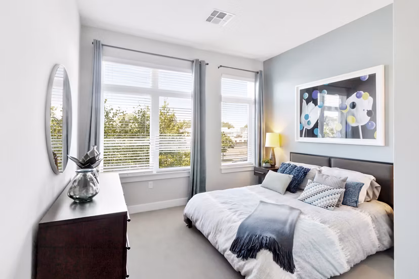 Elegant bedroom featuring modern furnishings and large windows at Re150 Apartments