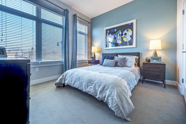 Elegant bedroom featuring modern furnishings and large windows at Re150 Apartments