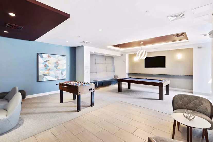 Modern clubhouse with cozy seating and large TV at Re150 Apartments