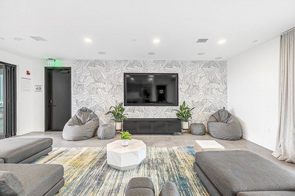 Spacious living room featuring modern furnishings and large windows at Rinrose Apartments