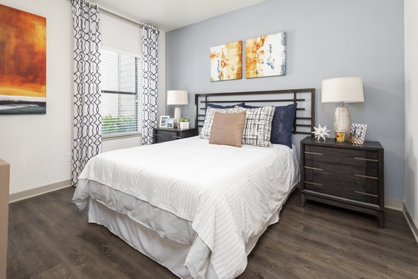 Modern bedroom with elegant decor in Solara Apartments, featuring a plush bed and ambient lighting for a cozy ambiance