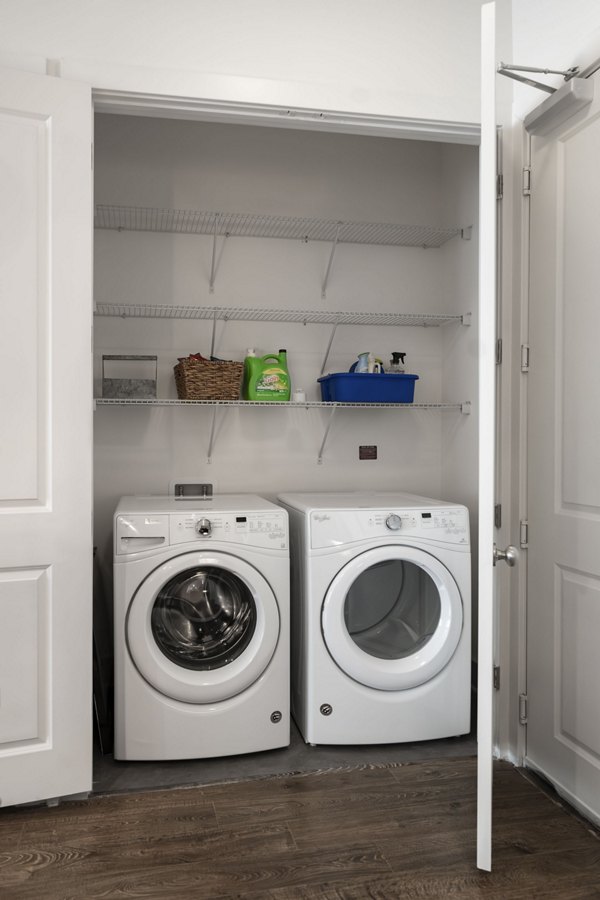 Laundry closet with a washing machine, dryer, and organized shelves at luxury apartments