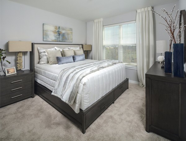 Cozy bedroom with elegant decor and large window at The Wexley at 100 Apartments, offering luxury living in a modern setting
