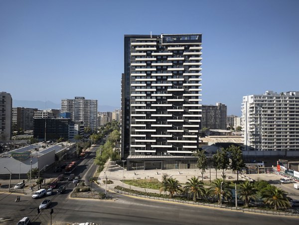 Modern high-rise building in an urban area with surrounding buildings and a clear sky.